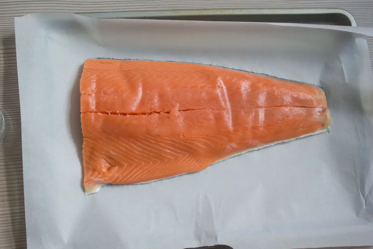 raw salmon on a lined baking tray.